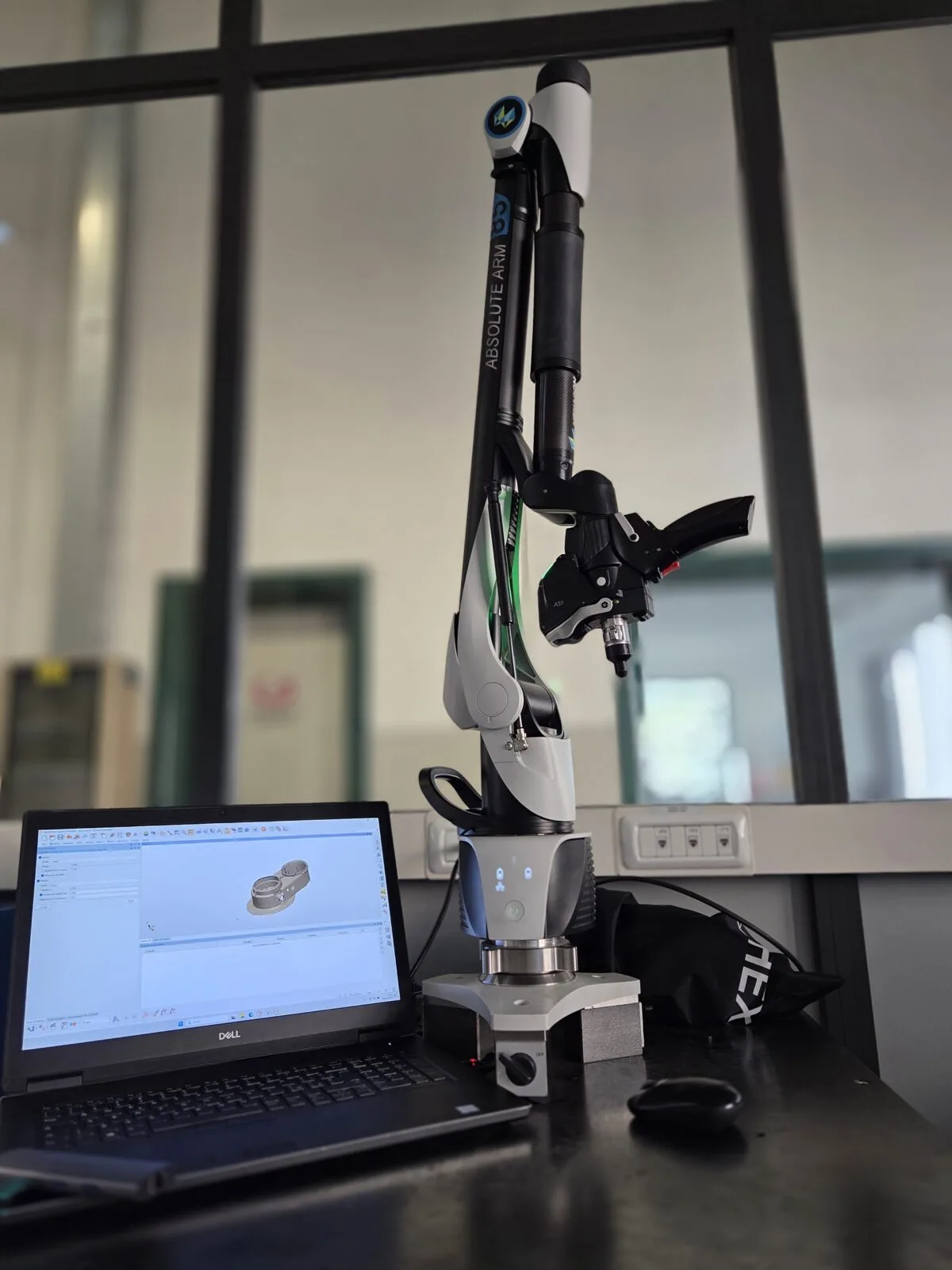 Braccio di misura laser accanto a un portatile che mostra il modello 3D del pezzo rilevato