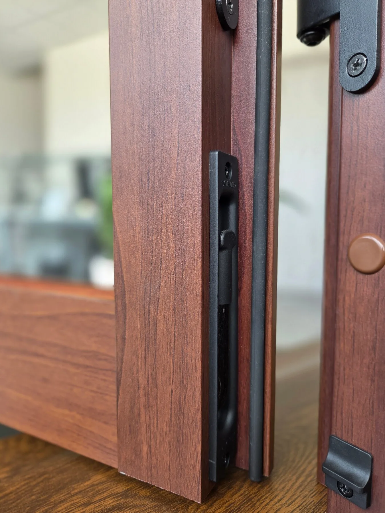 Dettaglio del bordo di un’anta in alluminio effetto legno, con cerniera e ferramenta a vista