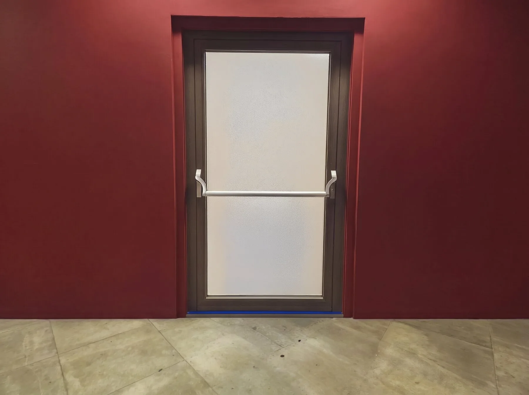 Porta di emergenza in alluminio con maniglione antipanico su parete rossa